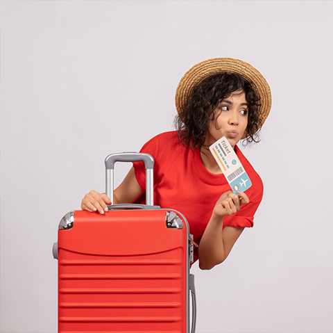A traveller holding a boarding pass beside her suitcase